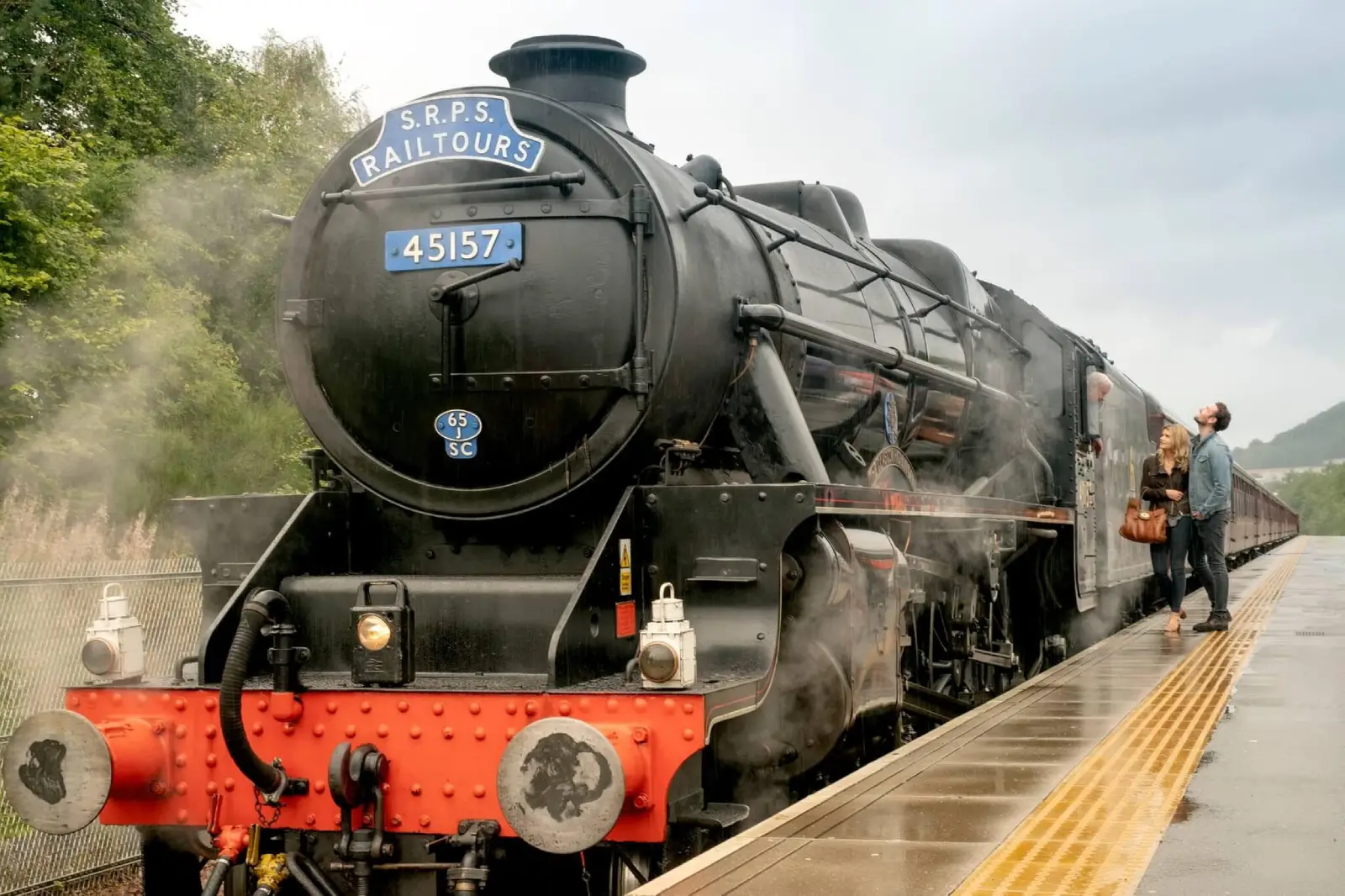 A couple admiring the Borders steam train from the platform at Tweedbank