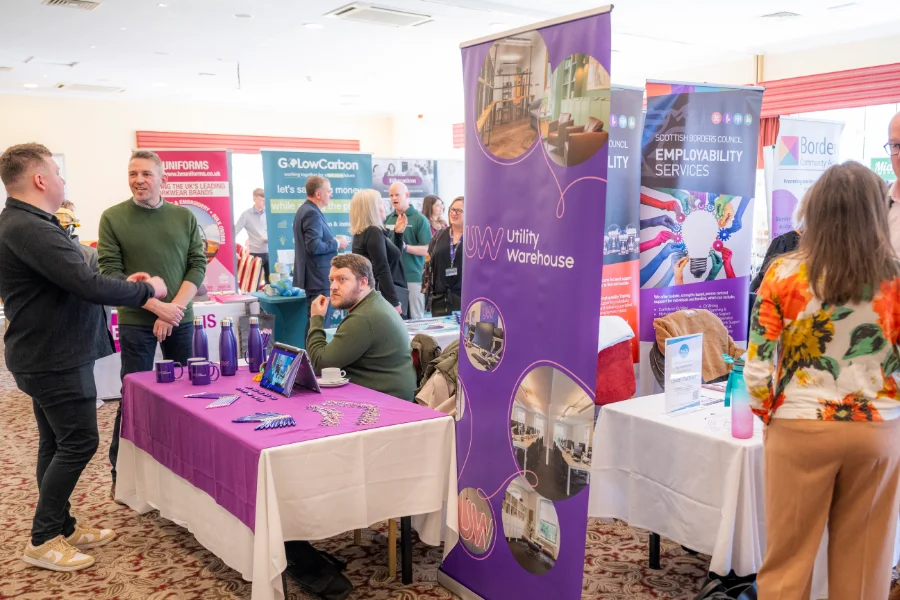 A busy market fair scene with several colourful booths and banners. People are interacting, creating a lively and engaging atmosphere.